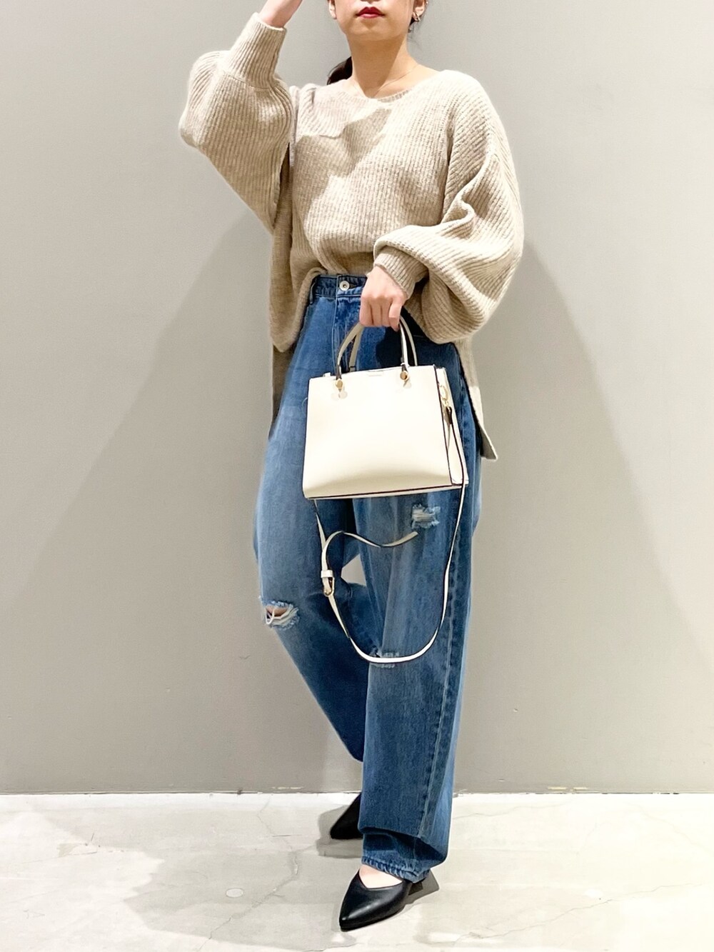 ブルー系のデニムパンツ、ホワイト系のショルダーバッグ、ブラック系のパンプスを着用したレディースの秋コーディネートの4枚目の写真
