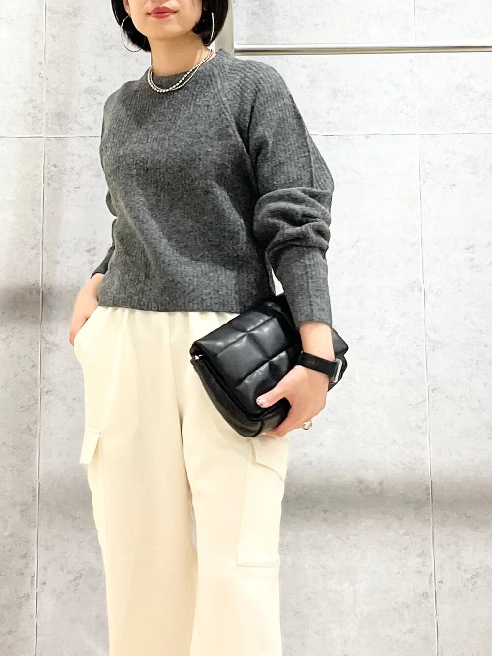 ブラック系のショルダーバッグ、ブラック系のパンプス、グレー系のニット/セーターを着用したレディースの秋コーディネートの6枚目の写真