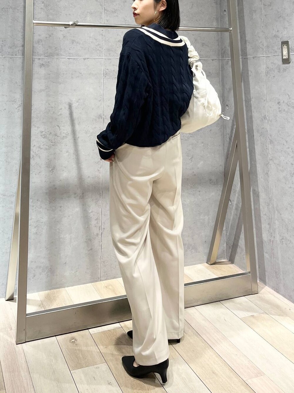 ブルー系のニット/セーター、ホワイト系のショルダーバッグ、ブラック系のパンプスを着用したレディースの冬コーディネートの4枚目の写真