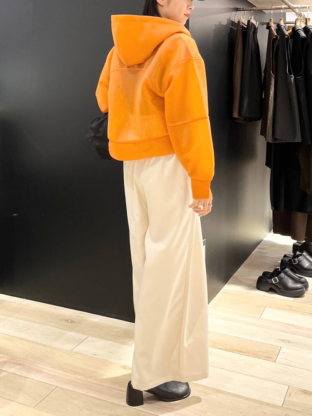 ホワイト系のタンクトップ、ブラック系のショルダーバッグ、オレンジ系のパーカーを着用したレディースの秋コーディネートの3枚目の写真