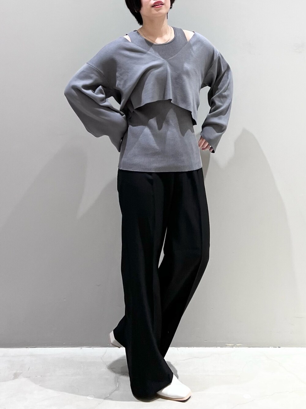 グレー系のニット/セーター、ブラック系のパンツ、ホワイト系のシューズを着用したレディースの春コーディネートの4枚目の写真