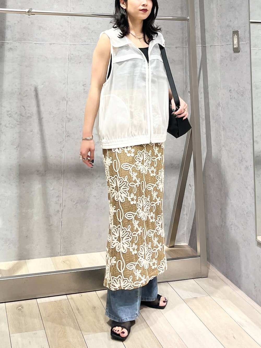 ブラック系のショルダーバッグ、ブルー系のデニムパンツ、ブラック系のサンダルを着用したレディースの春コーディネートの2枚目の写真