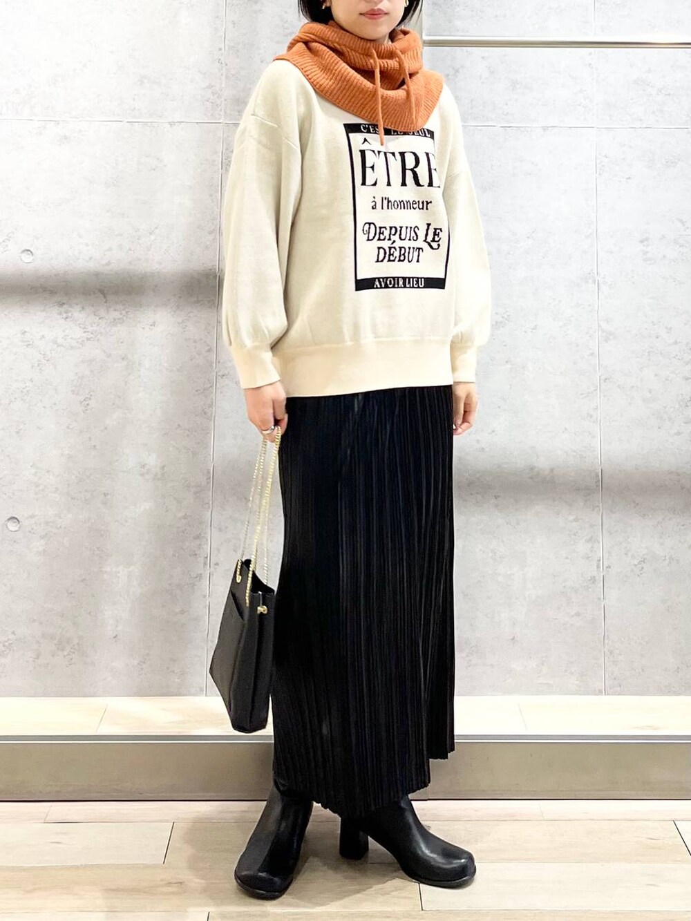 ブラック系のショルダーバッグ、ブラック系のブーツ、ホワイト系のニット/セーターを着用したレディースの秋コーディネートの7枚目の写真