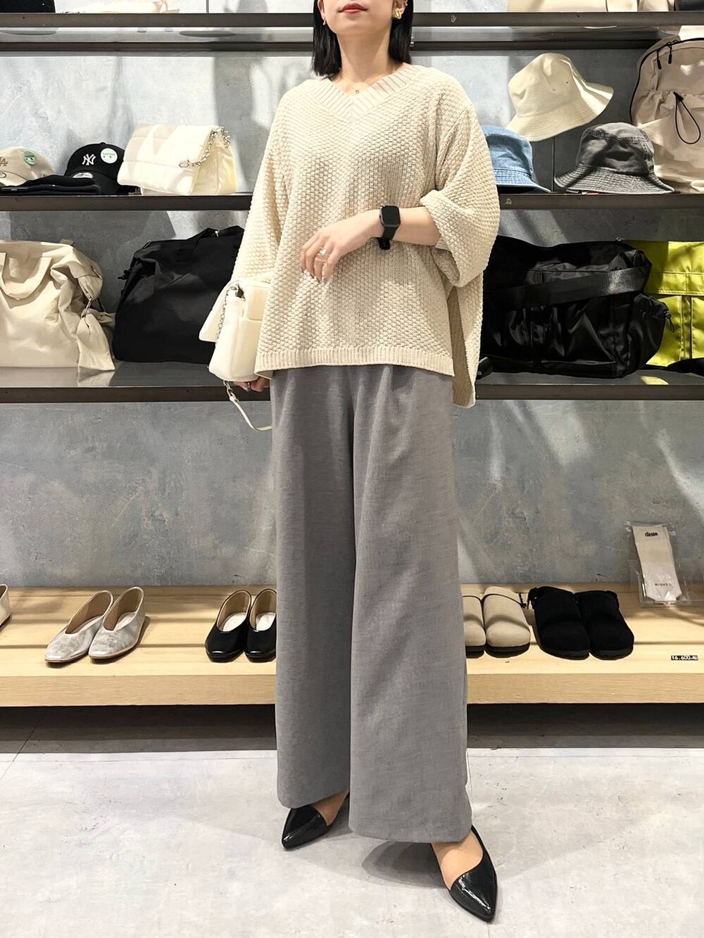 ホワイト系のショルダーバッグ、ホワイト系のニット/セーター、グレー系のスラックスを着用したレディースの春コーディネートの4枚目の写真