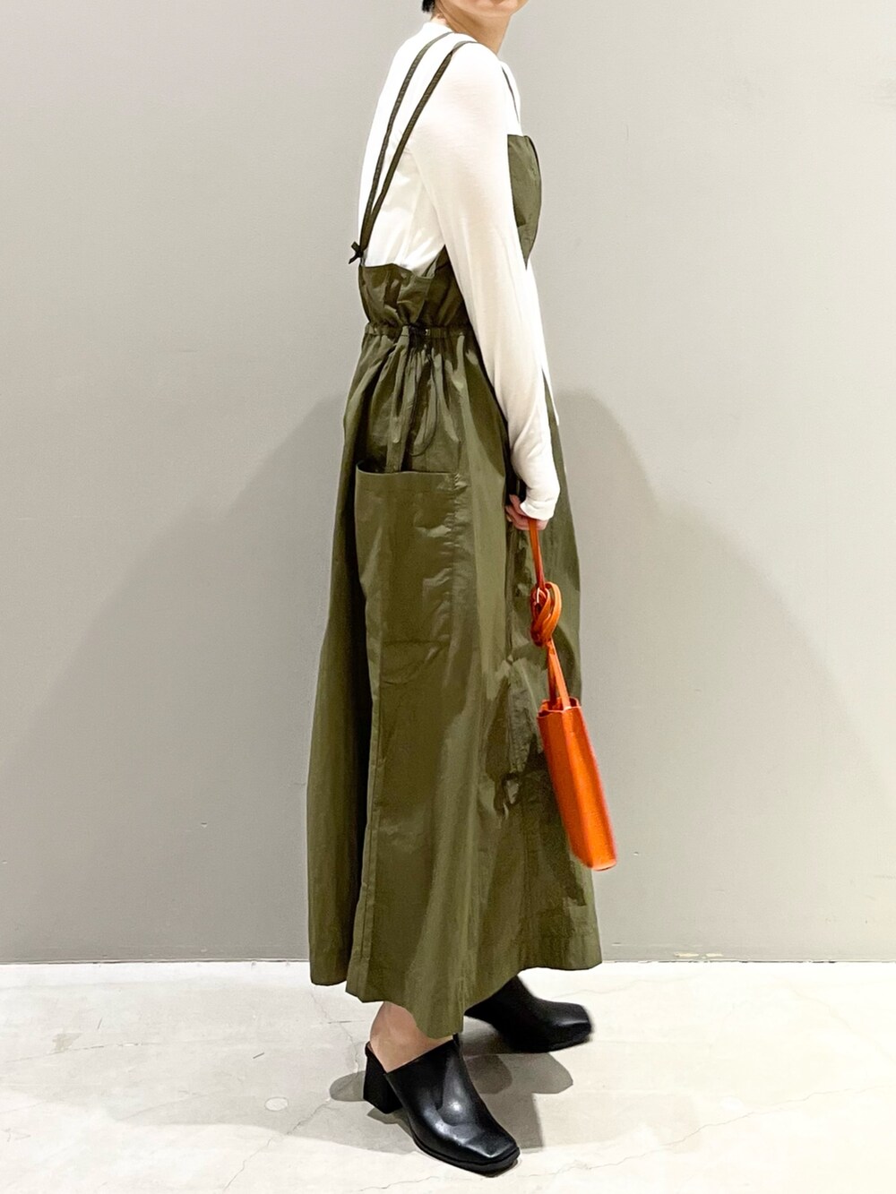 グリーン系のワンピース、オレンジ系のバッグ、ブラック系のサンダルを着用したレディースの春コーディネートの8枚目の写真