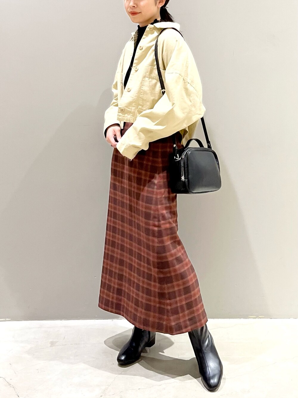 ブラック系のブーツ、レッド系のスカート、ブラック系のバッグを着用したレディースの秋コーディネートの4枚目の写真