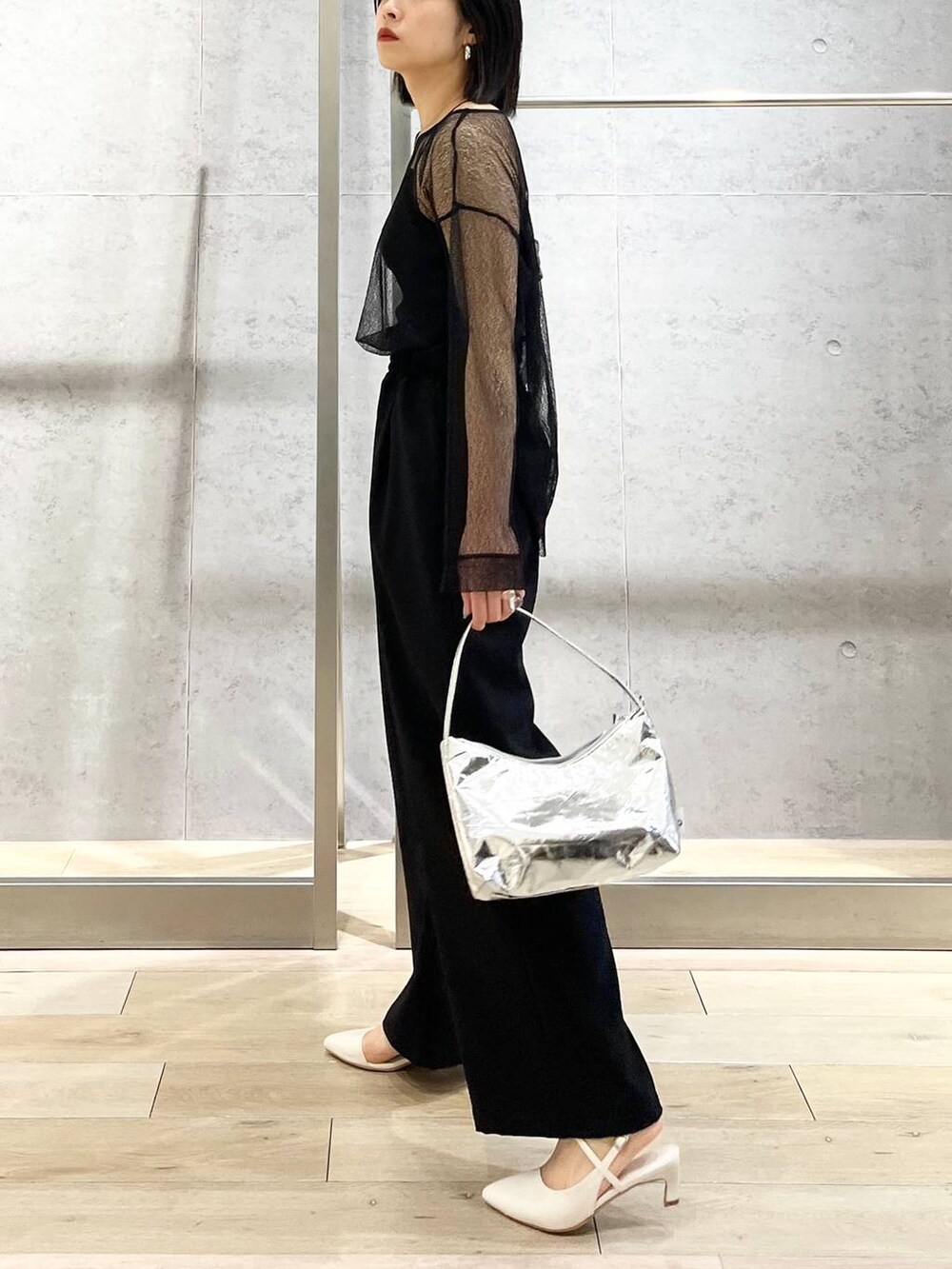 シルバー系のハンドバッグ、ブラック系のシャツ/ブラウス、ブラック系のスラックスを着用したレディースの冬コーディネートの6枚目の写真