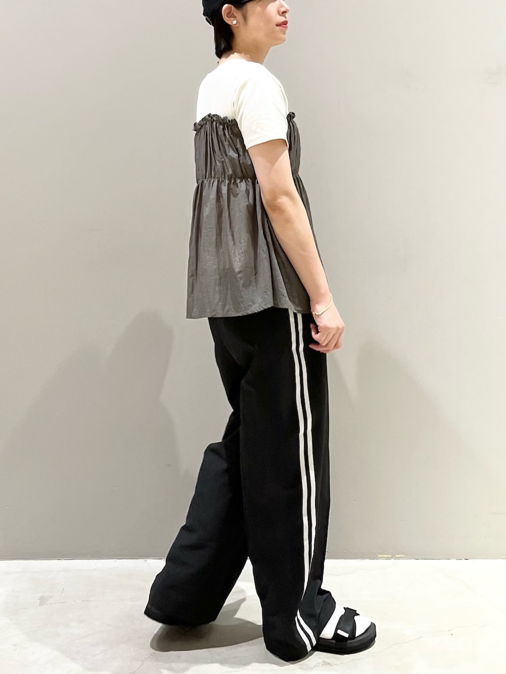 ブラック系のパンツ、ブラック系のサンダル、ゴールド系のハンドバッグを着用したレディースの秋コーディネートの3枚目の写真