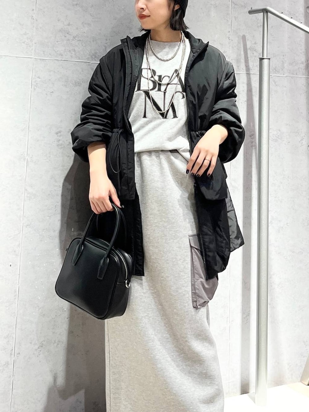 グレー系のスカート、ブラック系のボストンバッグ、ブラック系のブーツを着用したレディースの秋コーディネートの3枚目の写真