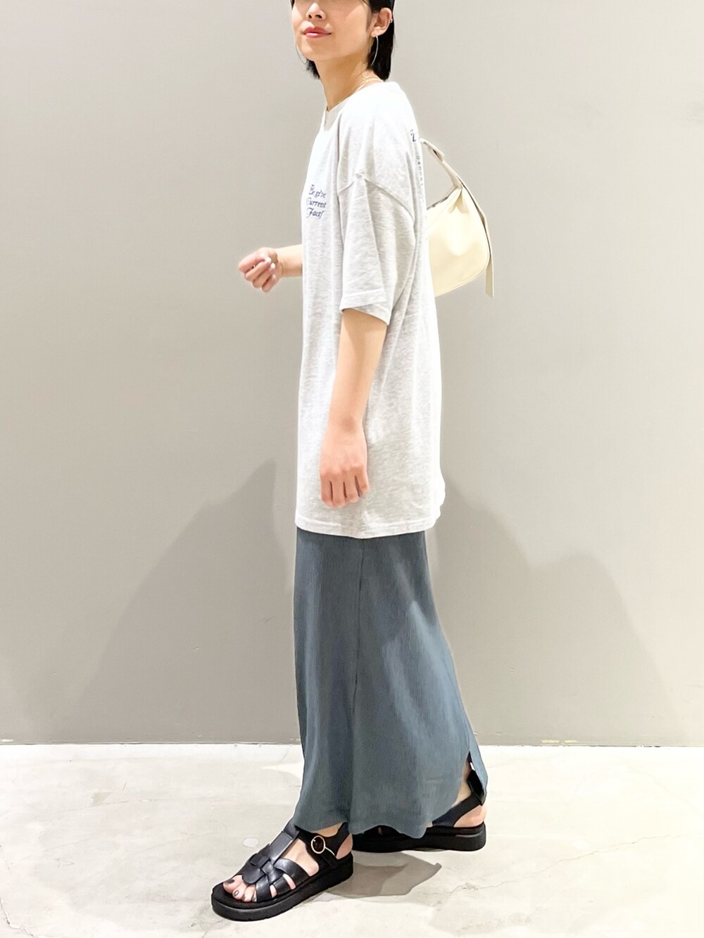 ホワイト系のショルダーバッグ、グリーン系のスカート、ブラック系のシューズを着用したレディースの夏コーディネートの7枚目の写真