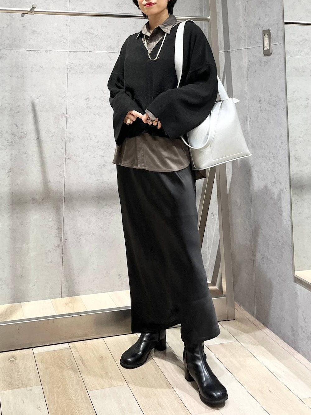 ブラック系のスカート、ブラック系のニット/セーター、グレー系のシャツ/ブラウスを着用したレディースの秋コーディネートの2枚目の写真