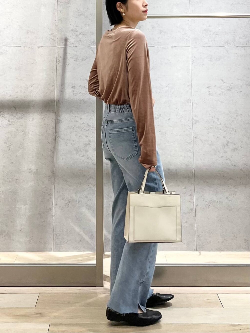 ブラック系のパンプス、ブルー系のデニムパンツ、ホワイト系のショルダーバッグを着用したレディースの秋コーディネートの7枚目の写真