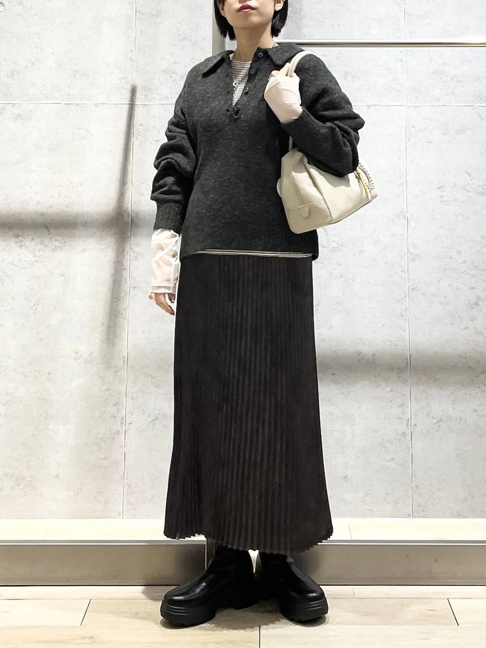 ホワイト系のTシャツ/カットソー、グレー系のスカート、ブラック系のブーツを着用したレディースの冬コーディネートの4枚目の写真