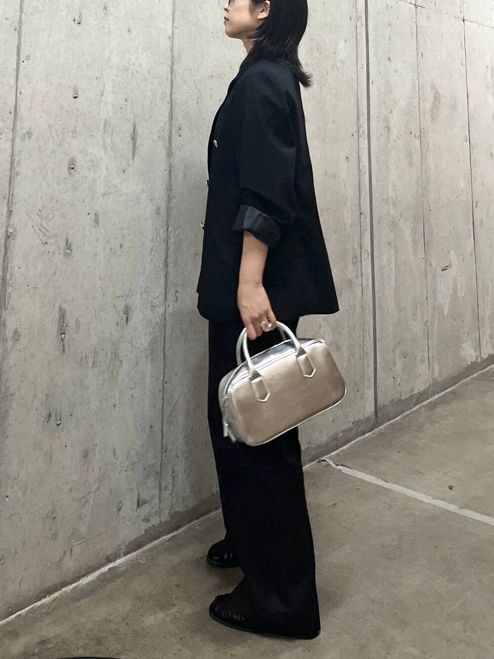 ブルー系のテーラードジャケット、シルバー系のボストンバッグ、グレー系のチノパンツを着用したレディースの秋コーディネートの5枚目の写真