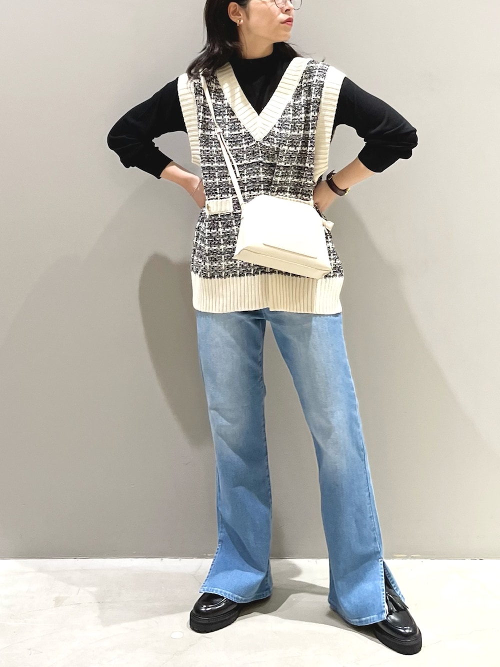 ブルー系のデニムパンツ、ブラック系のローファー、ホワイト系のショルダーバッグを着用したレディースの秋コーディネートの2枚目の写真