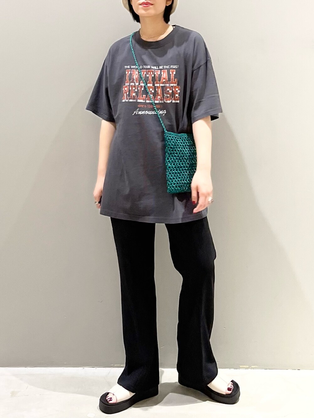 ブラック系のパンツ、ホワイト系のサンダル、グリーン系のショルダーバッグを着用したレディースの秋コーディネートの4枚目の写真