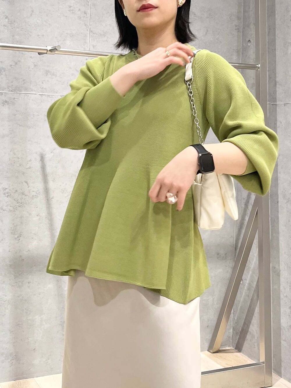 ホワイト系のショルダーバッグ、グリーン系のニット/セーター、ホワイト系のスカートを着用したレディースの春コーディネートの2枚目の写真