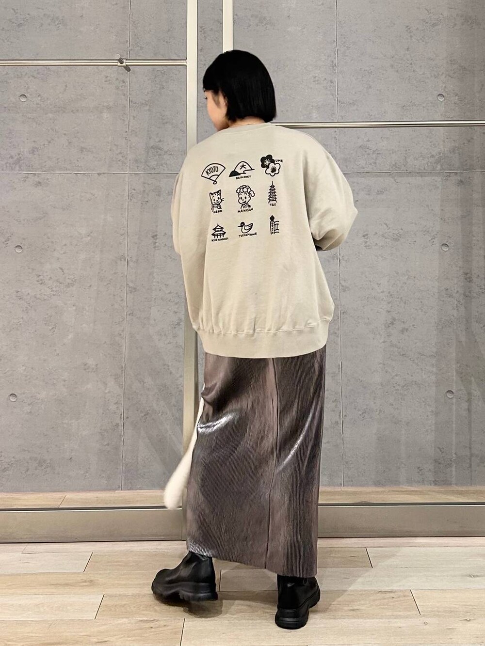 シルバー系のスカート、ブラック系のブーツ、ベージュ系のスウェットを着用したレディースの秋コーディネートの4枚目の写真