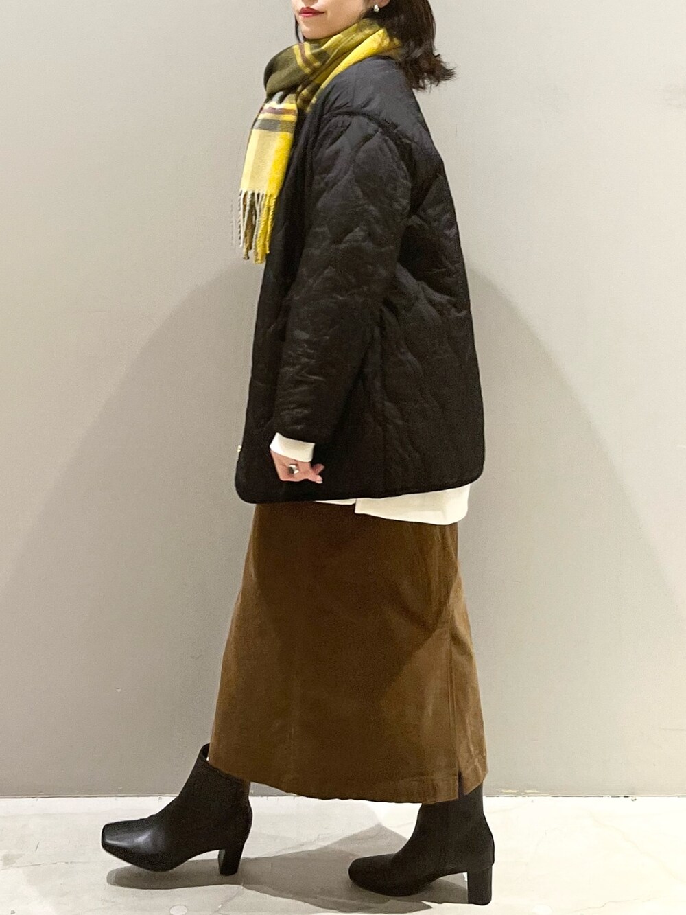 ブラウン系のスカート、ブラック系のブーツ、ブラック系のジャケット/アウターを着用したレディースの秋コーディネートの5枚目の写真