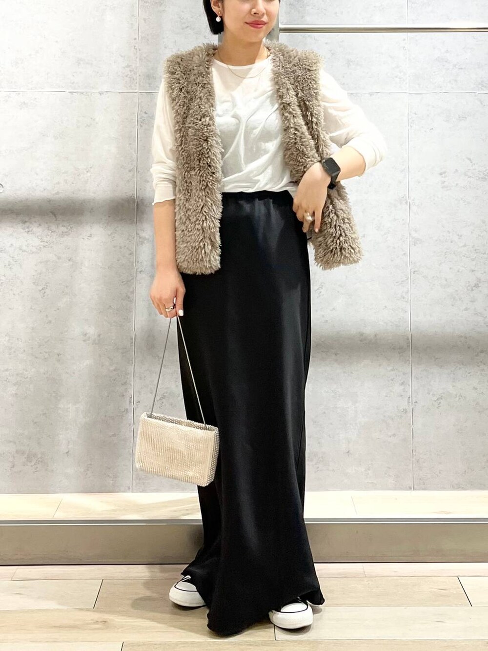 ブラック系のキャミソール、ベージュ系のベスト、ホワイト系のTシャツ/カットソーを着用したレディースの秋コーディネートの6枚目の写真