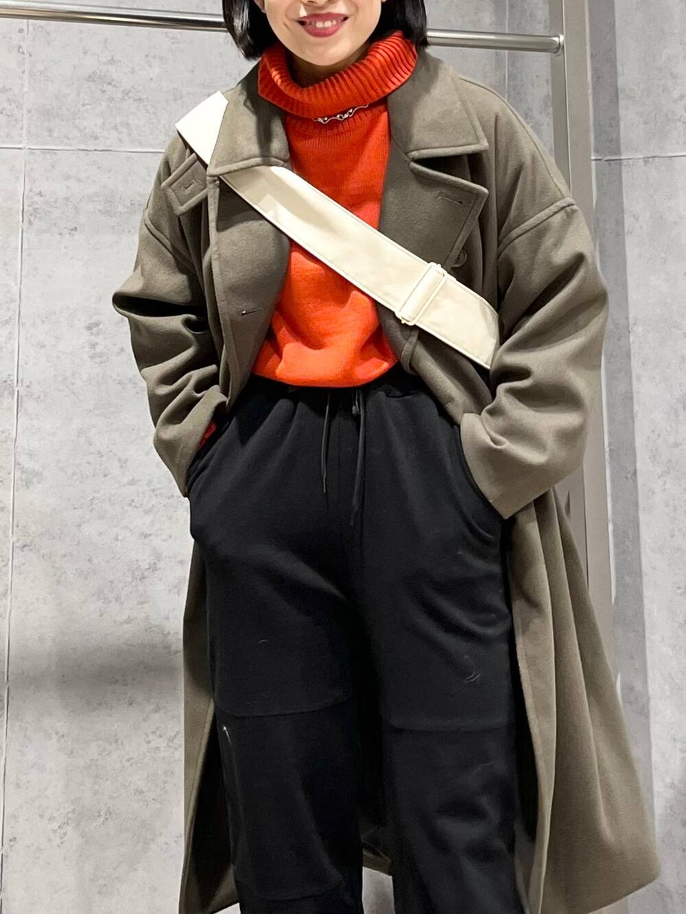 レッド系のニット/セーター、グリーン系のチェスターコート、ブラック系のブーツを着用したレディースの冬コーディネートの8枚目の写真