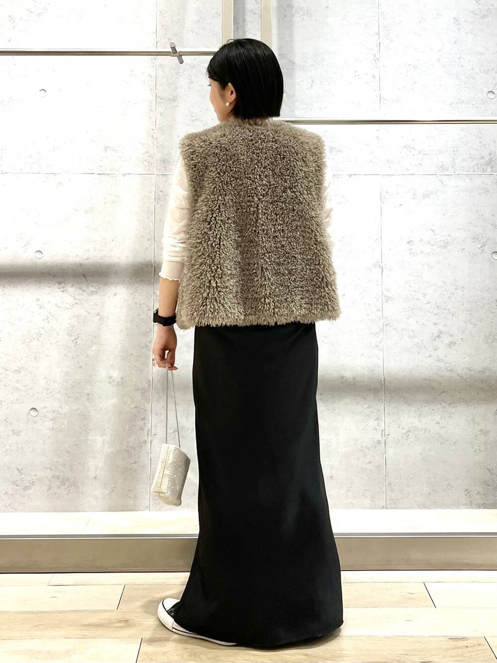 ブラック系のキャミソール、ベージュ系のベスト、ホワイト系のTシャツ/カットソーを着用したレディースの秋コーディネートの4枚目の写真