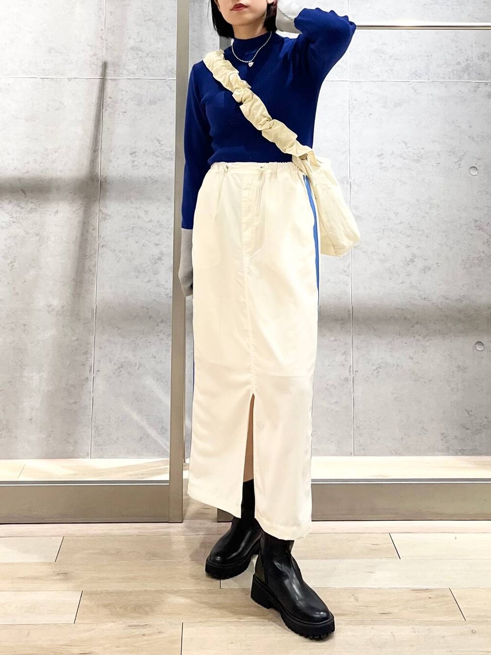 ブラック系のブーツ、ホワイト系のショルダーバッグ、ホワイト系のスカートを着用したレディースの冬コーディネートの4枚目の写真