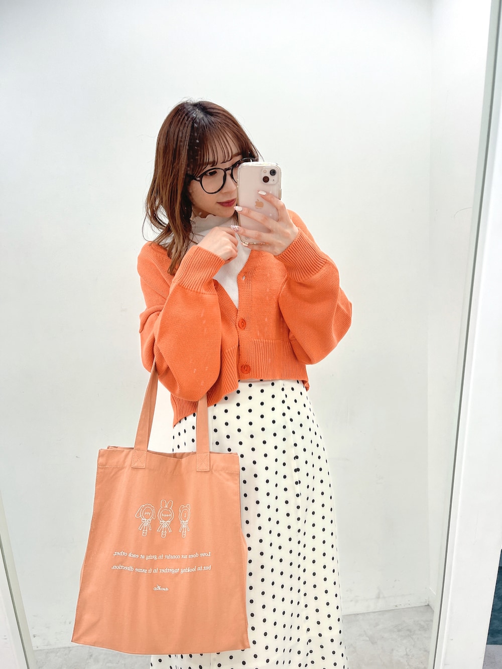 オレンジ系のカーディガン/ボレロ、ホワイト系のショルダーバッグ、ホワイト系のスカートを着用したレディースの冬コーディネートの2枚目の写真