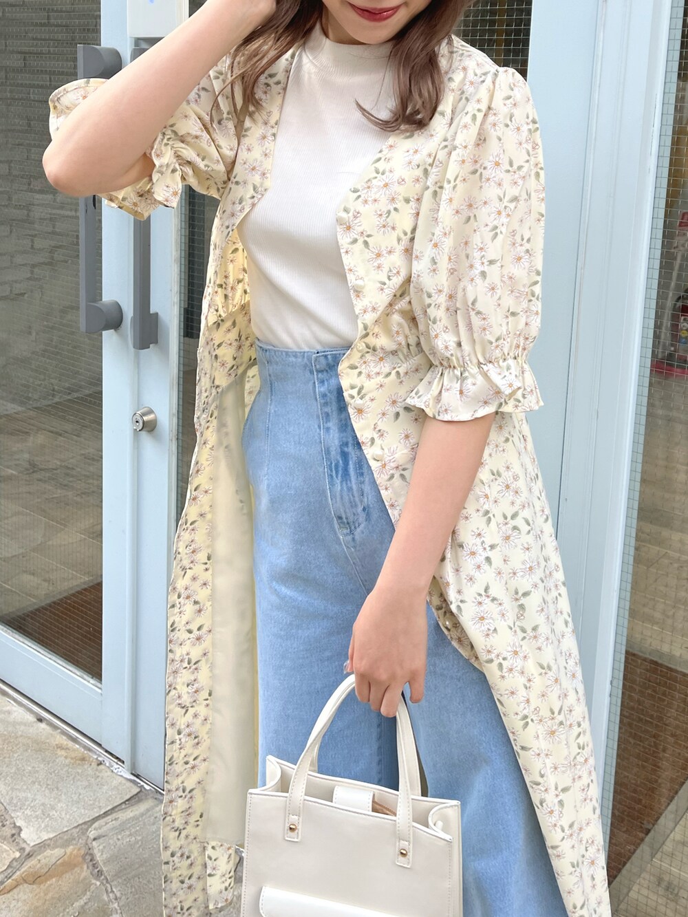 イエロー系のワンピース、ブルー系のデニムパンツ、ホワイト系のショルダーバッグを着用したレディースの春コーディネートの3枚目の写真