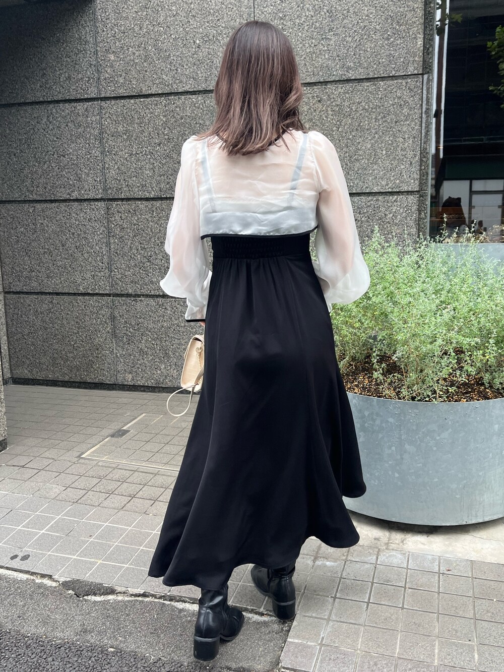 ブラック系のワンピース、ホワイト系のショルダーバッグ、ブラック系のブーツを着用したレディースの秋コーディネートの2枚目の写真