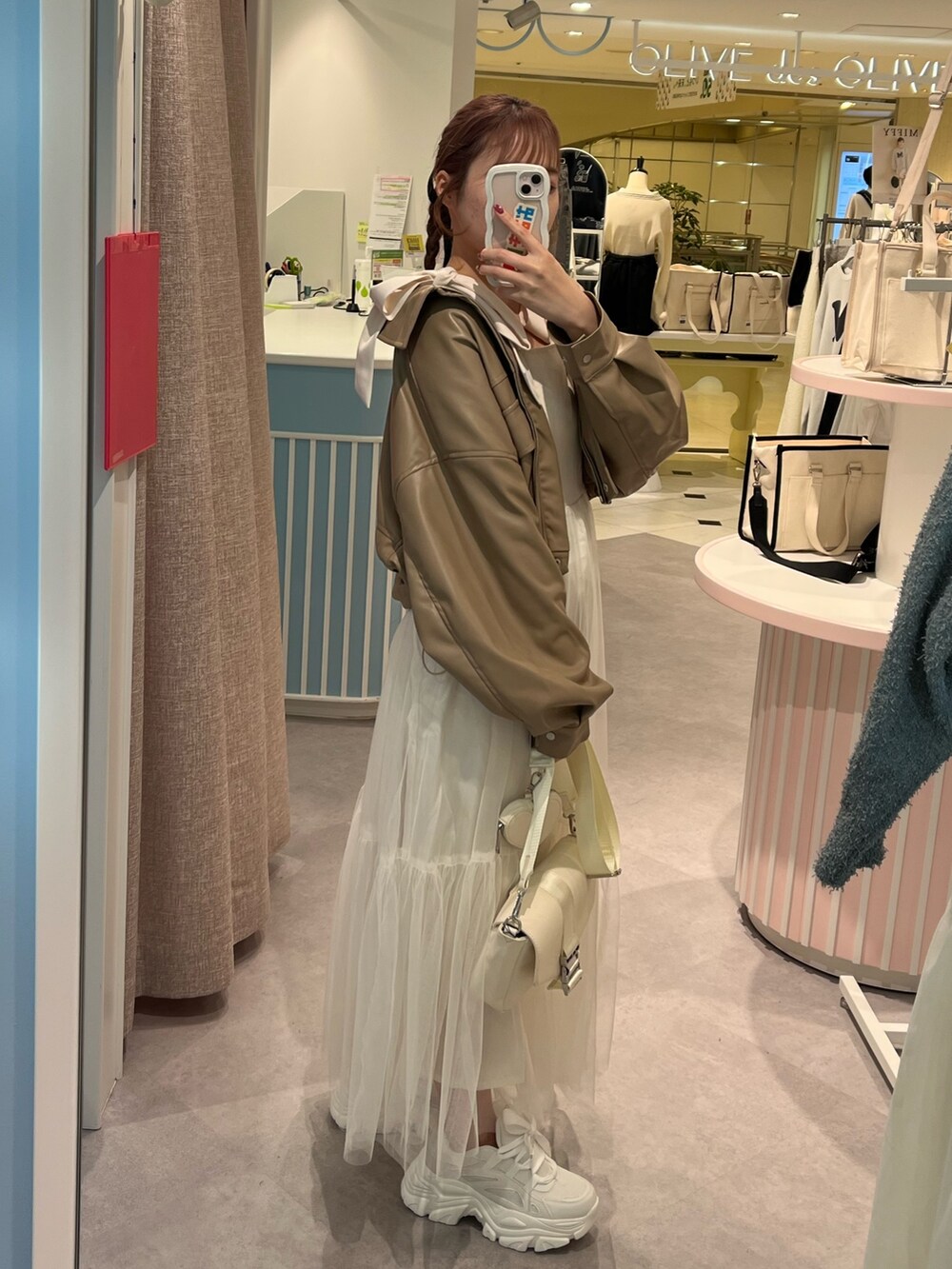 ブラウン系のブルゾン、ホワイト系のワンピース、イエロー系のショルダーバッグを着用したレディースの冬コーディネートの2枚目の写真