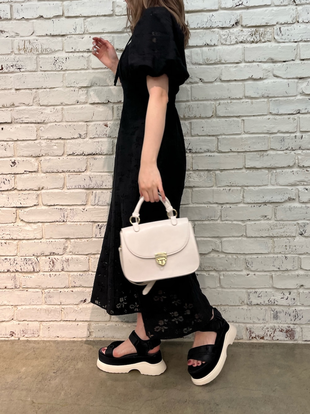 ブラック系のワンピース、ホワイト系のショルダーバッグ、ブラック系のサンダルを着用したレディースの春コーディネートの2枚目の写真
