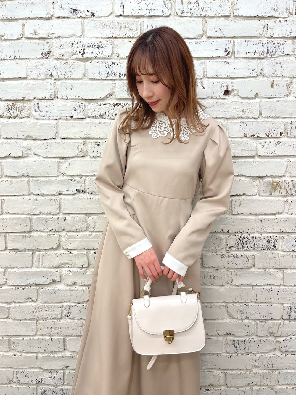 ベージュ系のワンピース、ホワイト系のショルダーバッグ、ブラウン系のローファーを着用したレディースの冬コーディネートの2枚目の写真