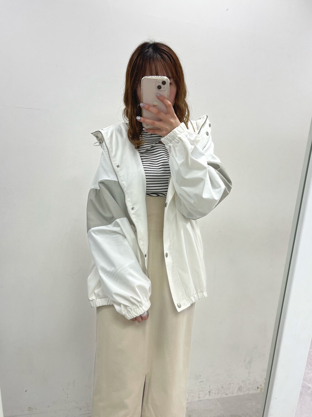 ホワイト系のマウンテンパーカー、ホワイト系のTシャツ/カットソー、ホワイト系のスカートを着用したレディースの冬コーディネートの2枚目の写真