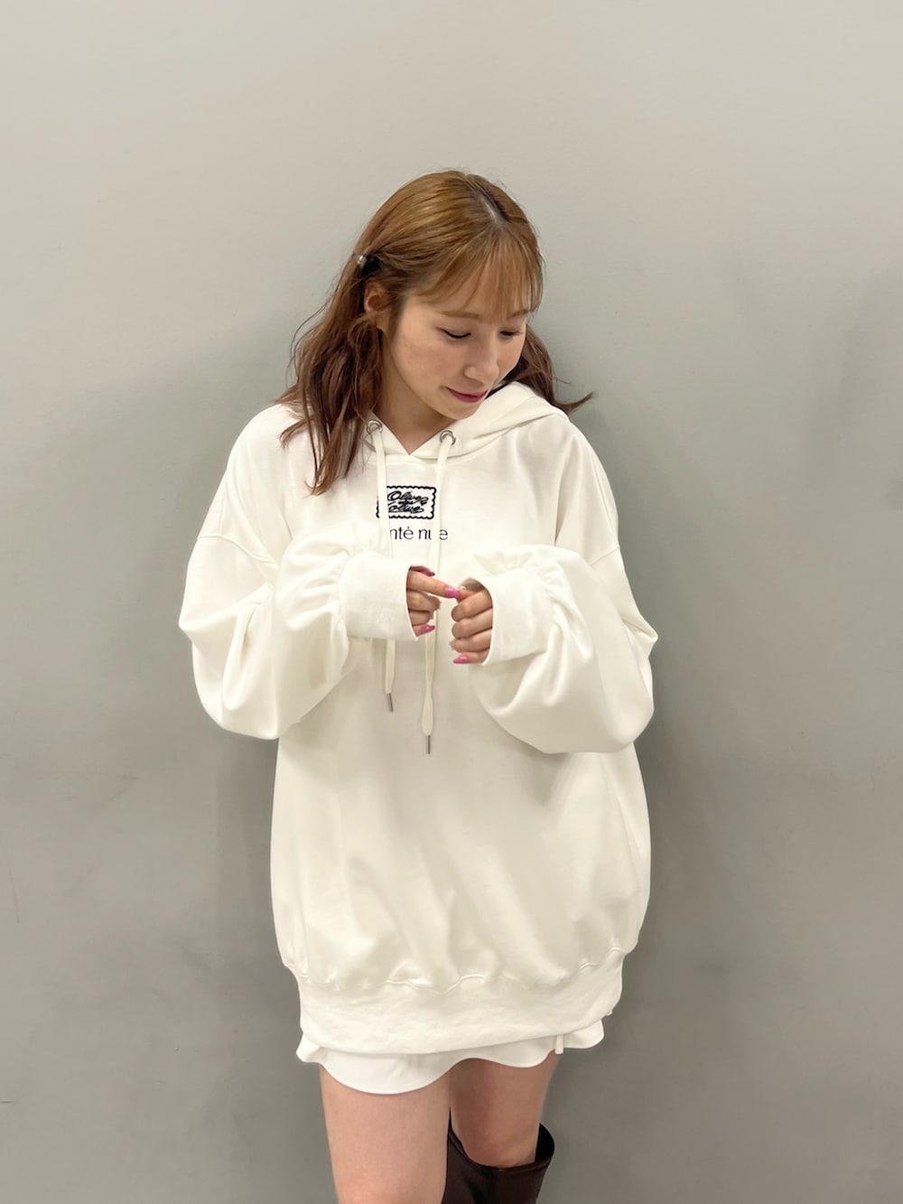 ホワイト系のパーカー、ブラウン系のブーツを着用したレディースの夏コーディネートの2枚目の写真