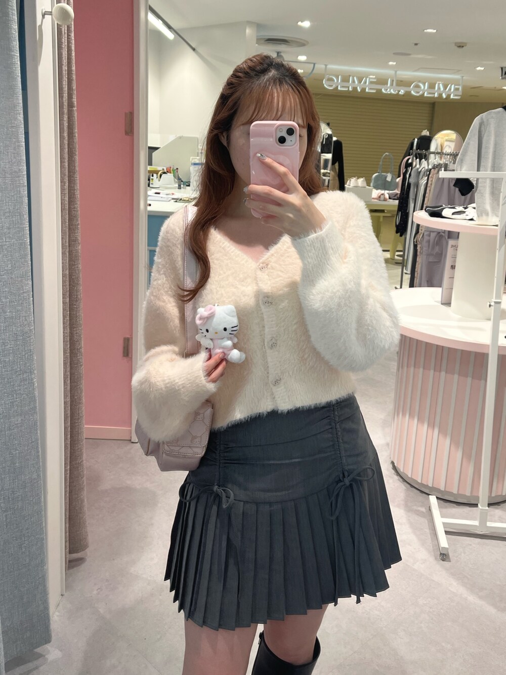 ピンク系のカーディガン/ボレロ、グレー系のスカート、ブラック系のブーツを着用したレディースの秋コーディネートの2枚目の写真