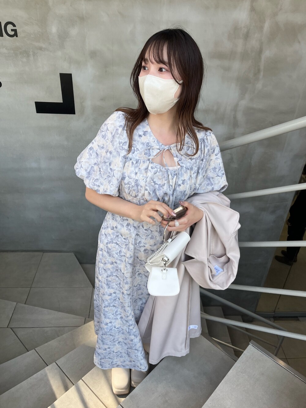 グレー系のワンピース、ベージュ系のトレンチコート、ホワイト系のサンダルを着用したレディースの春コーディネートの4枚目の写真