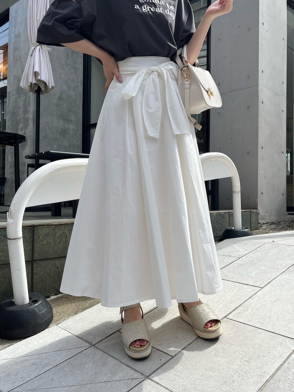 ブラック系のTシャツ/カットソー、ホワイト系のスカート、ゴールド系のサンダルを着用したレディースの春コーディネートの4枚目の写真