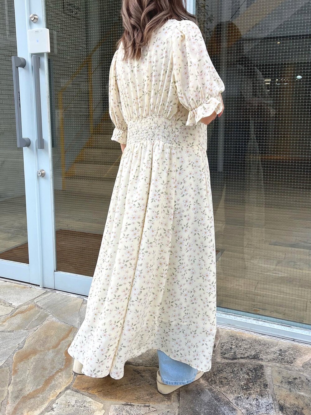 イエロー系のワンピース、ブルー系のデニムパンツ、ホワイト系のサンダルを着用したレディースの春コーディネートの3枚目の写真