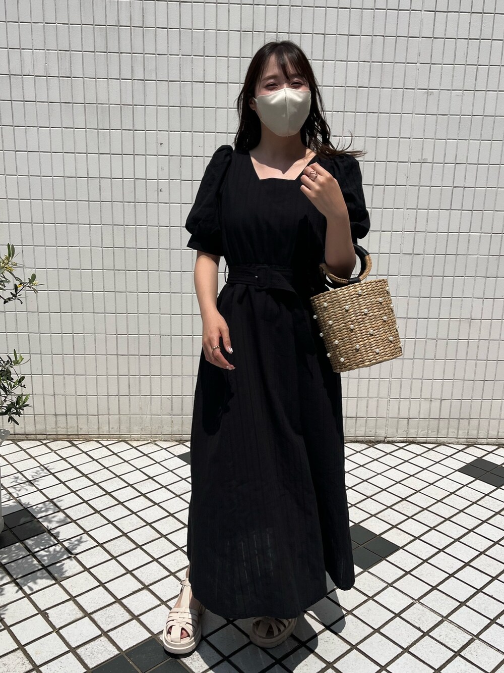 ブラック系のワンピース、ベージュ系のかごバッグ、ブラック系のサンダルを着用したレディースの春コーディネートの2枚目の写真