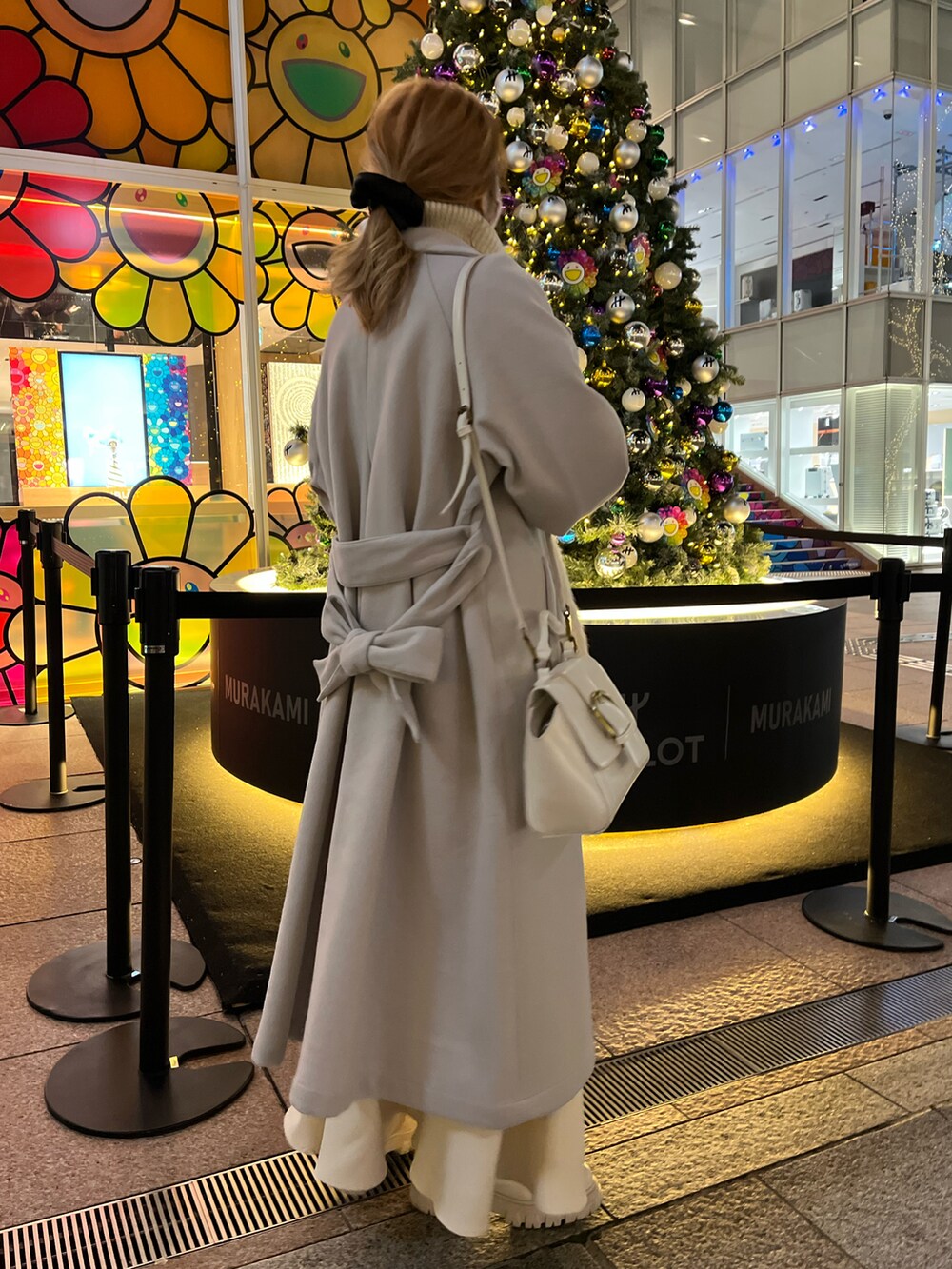 ホワイト系のショルダーバッグ、グレー系のステンカラーコート、ホワイト系のニット/セーターを着用したレディースの冬コーディネートの2枚目の写真