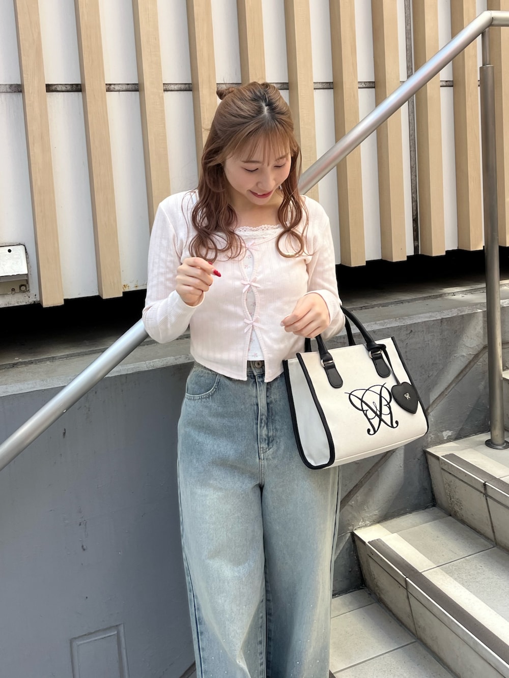 ピンク系のTシャツ/カットソー、ブルー系のデニムパンツ、ベージュ系のトートバッグを着用したレディースの春コーディネートの2枚目の写真