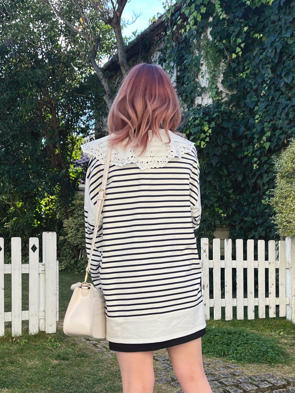 ホワイト系のTシャツ/カットソー、ブラック系のスカート、ホワイト系のブーツを着用したレディースの冬コーディネートの3枚目の写真