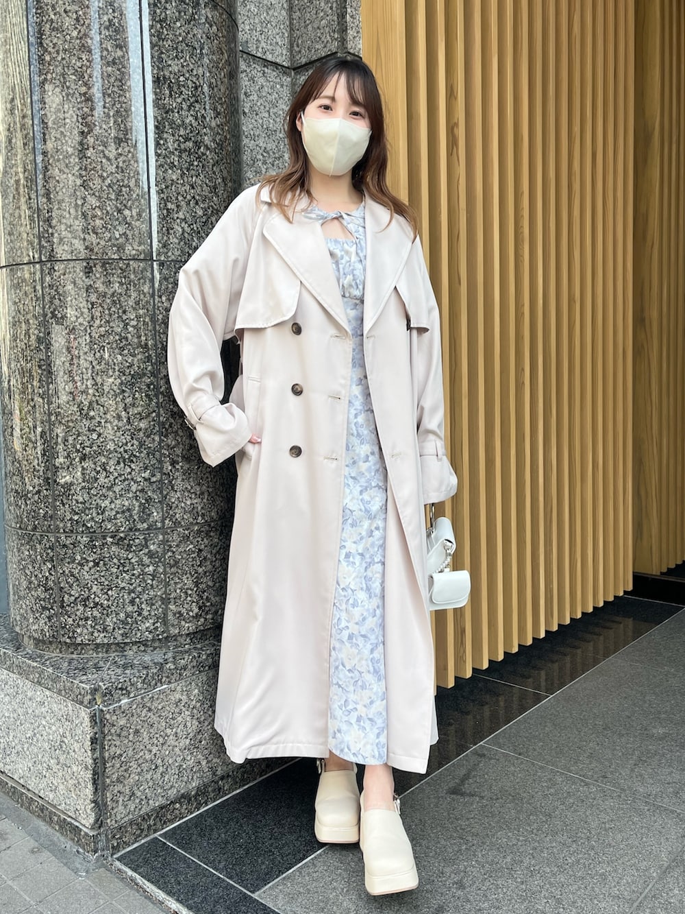 グレー系のワンピース、ベージュ系のトレンチコート、ホワイト系のサンダルを着用したレディースの春コーディネートの2枚目の写真