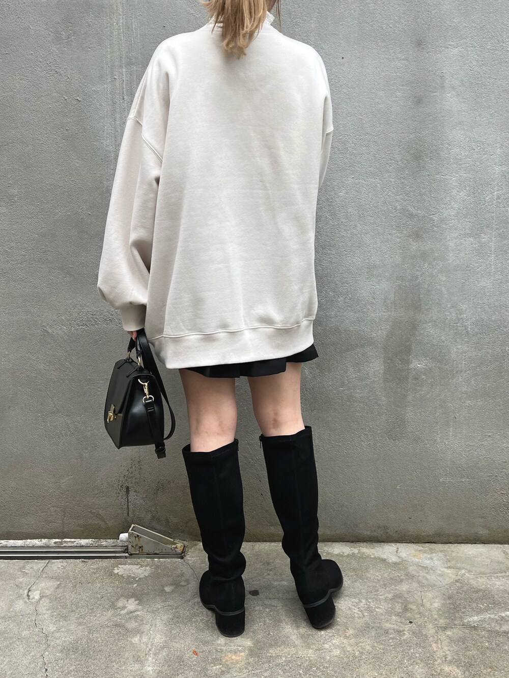 ホワイト系のスウェット、ブラック系のスカート、ブラック系のブーツを着用したレディースの冬コーディネートの2枚目の写真