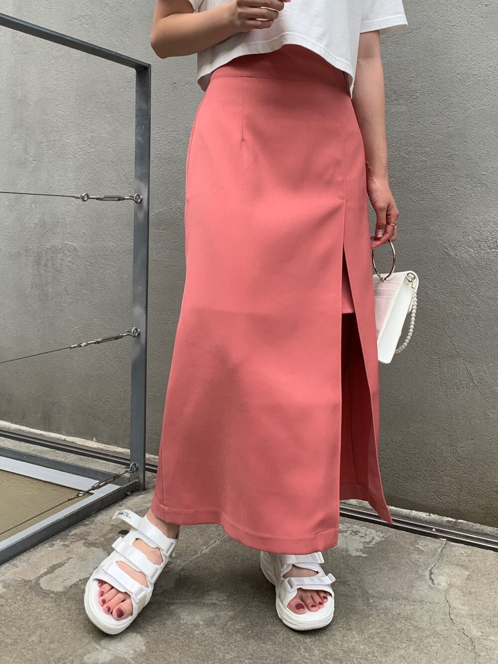 ホワイト系のTシャツ/カットソー、ピンク系のスカート、ホワイト系のサンダルを着用したレディースの夏コーディネートの2枚目の写真