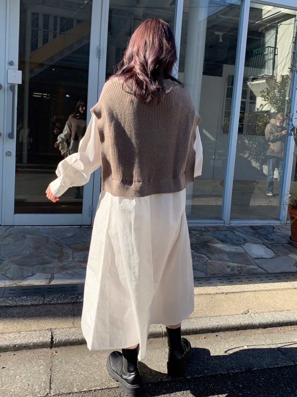 ベージュ系のワンピース、ブラック系のブーツ、ブラック系のショルダーバッグを着用したレディースの春コーディネートの2枚目の写真