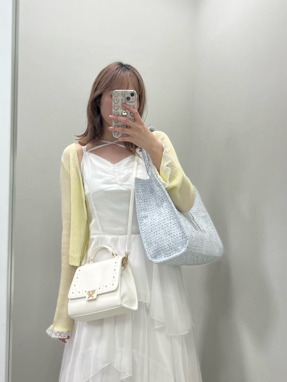 ホワイト系のトートバッグ、ホワイト系のワンピース、イエロー系のカーディガン/ボレロを着用したレディースの春コーディネートの2枚目の写真