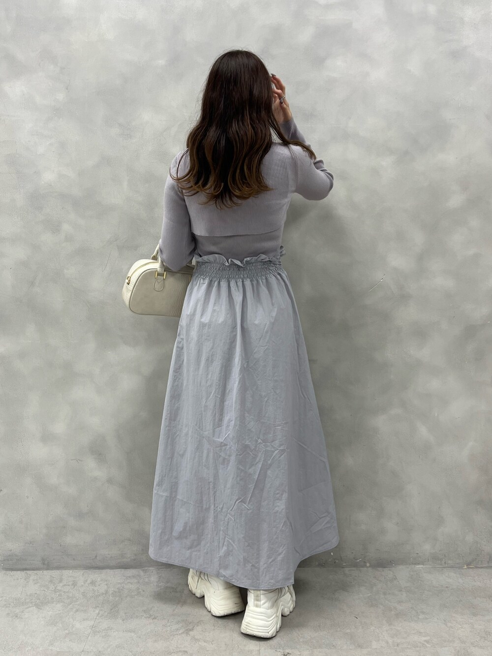 パープル系のワンピース、ホワイト系のショルダーバッグ、ホワイト系のスニーカーを着用したレディースの秋コーディネートの2枚目の写真