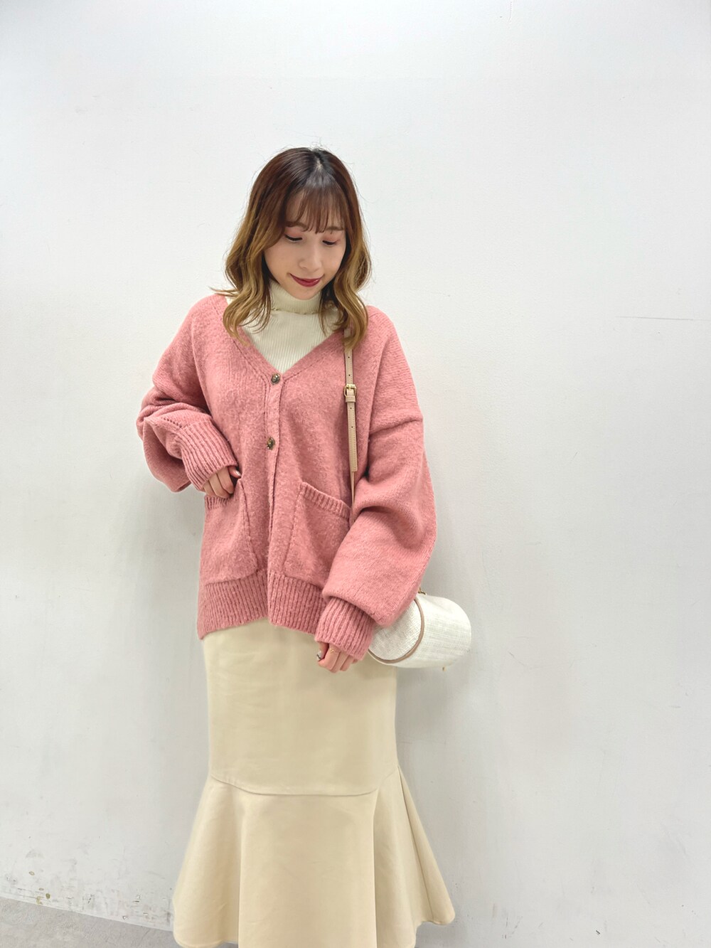ピンク系のカーディガン/ボレロ、ホワイト系のニット/セーター、ホワイト系のスカートを着用したレディースの秋コーディネートの2枚目の写真